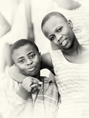 A Ghanaian girl gives a hug to her brother clipart