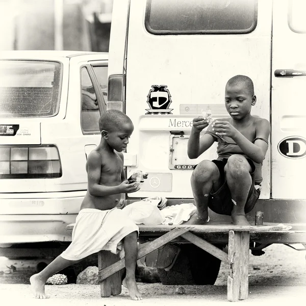 Двое детей из Ганы сидят на скамейке у дороги — стоковое фото