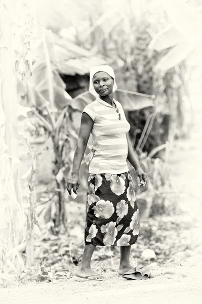 Una mujer ghanesa camina frente a las plantas verdes —  Fotos de Stock