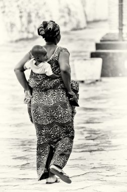 A Ghanaian woman carries her baby on her back clipart