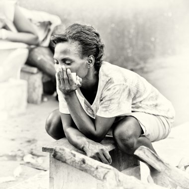 A Ghanaian woman poses sitting on a bench clipart