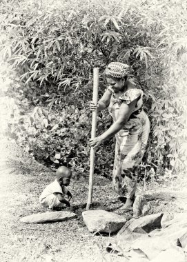 Gana'lı bir kadın kazılar ve bebeğini izliyor
