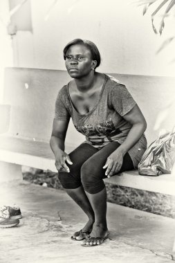 A Ghanaian woman sits on a bench clipart