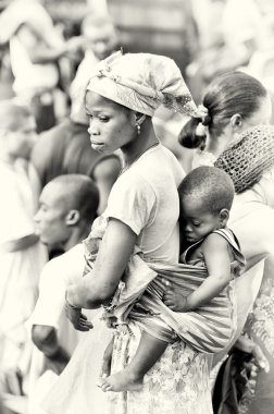 A little Ghanaian baby sleeps on his mother back clipart