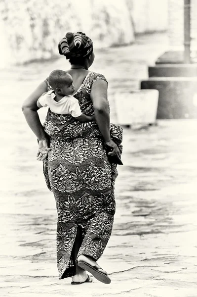Een Ghanese vrouw draagt haar baby op haar rug — Stockfoto