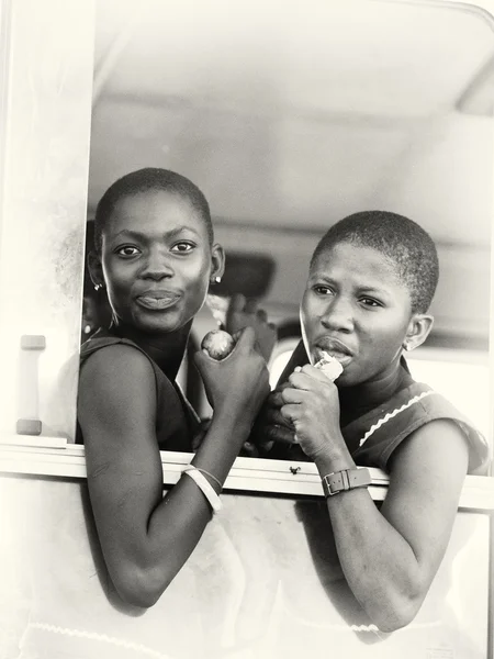 Twee Ghanese dames horloge van het venster en eten — Stockfoto