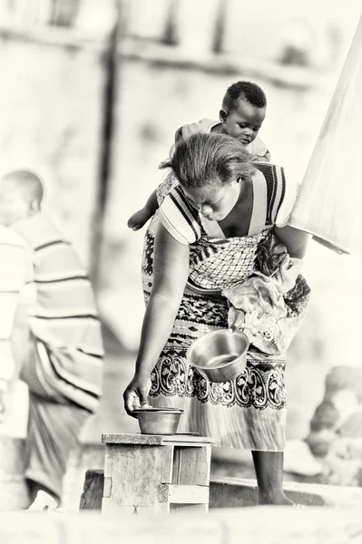 一位抱着婴儿的加纳女士选择这道菜 — 图库照片