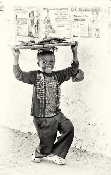 Un chico ghanés con el pez sobre la cabeza posa para la cámara — Foto de Stock