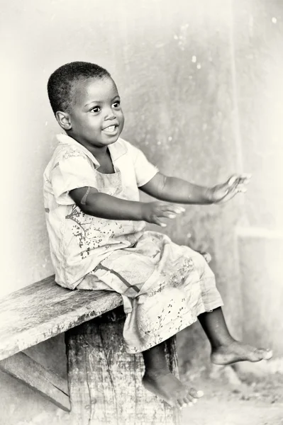 Little Ghanaian girl relaxes on a bench — Stock Photo, Image