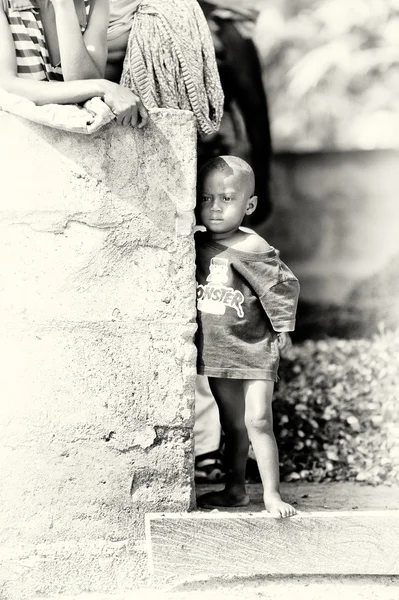 Kleiner ghanaischer Junge versteckt sich in der Nähe des Steins — Stockfoto