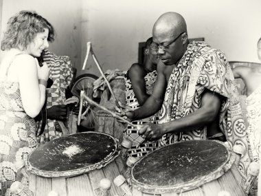 A man in glasses from Ghana plays the drums clipart