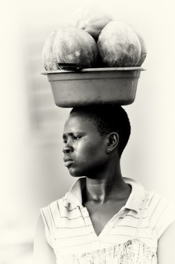 A woman from Ghana carries the melons on her head clipart