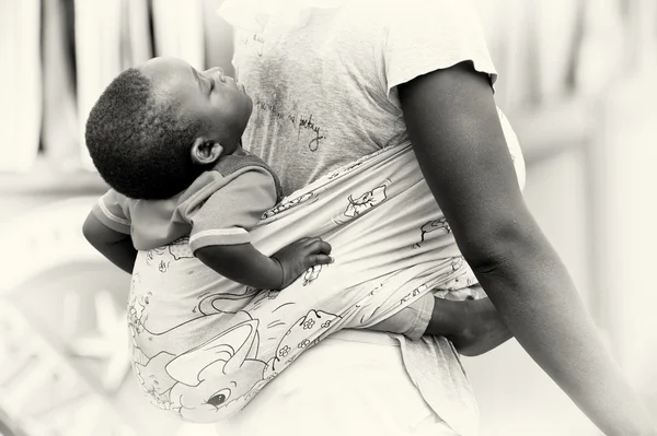 Un niño pequeño de Ghana duerme en la espalda de su madre — Foto de Stock
