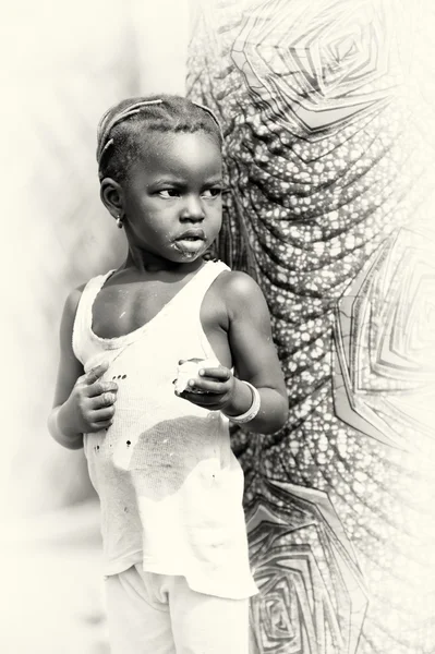 Little girl from Ghana eats something near a tree — Stock Photo, Image