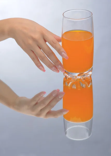 Рука держит стакан оранжевой жидкости — стоковое фото