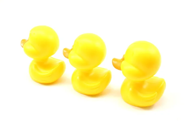 Üç sarı oyuncak ördek uzakta Yüzme — Stok fotoğraf