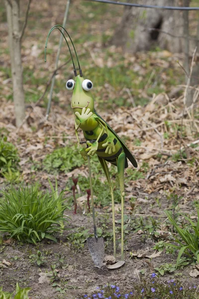 シャベルの庭の彫像を持つ緑のバッタ — ストック写真