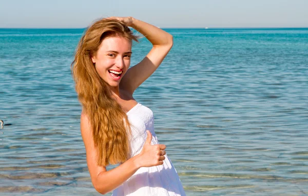 Улыбающаяся девушка с длинными волосами на пляже — стоковое фото