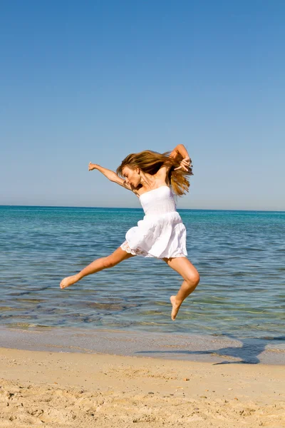 Szczęśliwa młoda kobieta piękne skoki na plaży — Zdjęcie stockowe