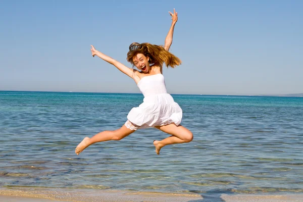 Happy young beautiful woman jumping on the beach — Stock Photo, Image