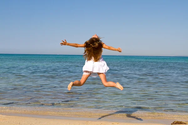 Счастливая молодая красивая женщина прыгает на пляже — стоковое фото