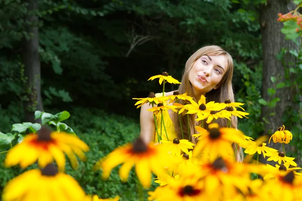 Porträtt av en ung kvinna på nära håll i skogen med blommor — Stockfoto