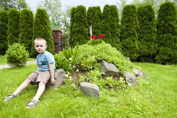Boy among flowers and other plants — Stock Photo, Image