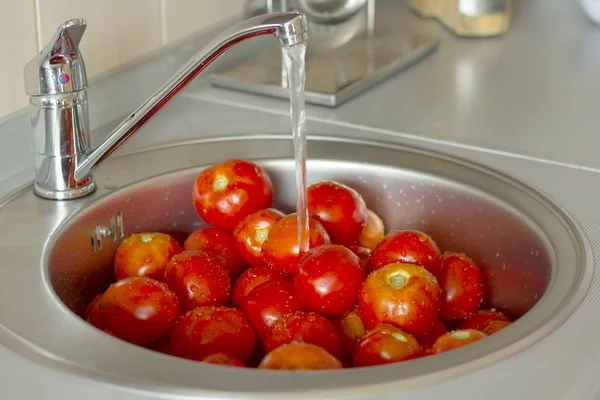 Tomatoes in a sink with water drops