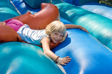 Girl playing on an inflatable toy clipart