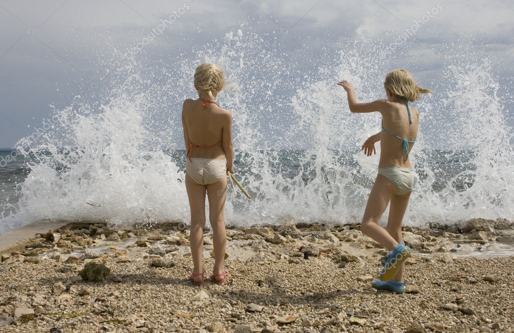 Δύο μικρά κορίτσια να παίζουν στην παραλία με το undertow 