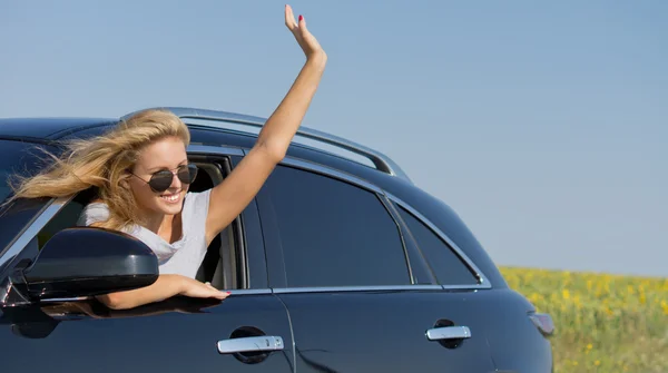 Mujer saludando desde la ventana del coche — Foto de Stock