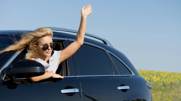 Mujer inclinada desde la ventana del coche saludando — Foto de Stock