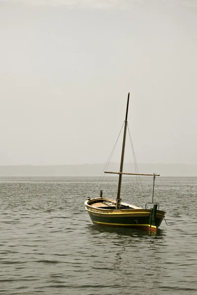 Рыбацкая лодка с мачтой в море — стоковое фото