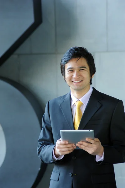 Azjatycki biznes człowiek ubrany w garnitur i krawat, uśmiechając się z tabletem — Zdjęcie stockowe