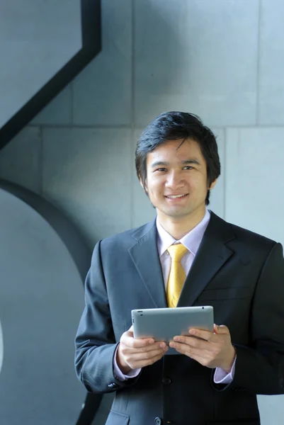 Asiatischer Geschäftsmann in Anzug und Krawatte, lächelnd mit Tablet — Stockfoto