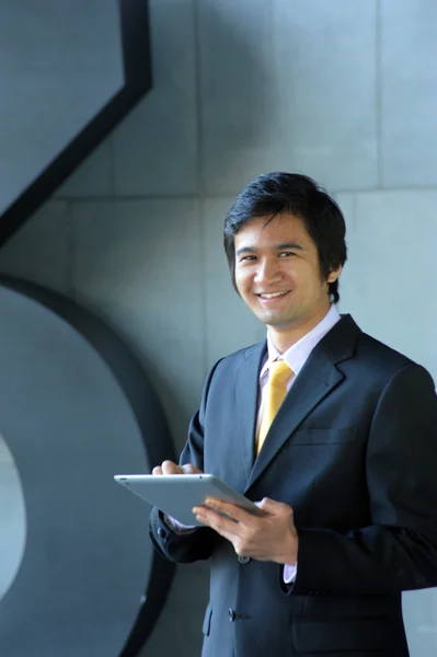 Asiatico uomo d'affari vestito in abito e cravatta, sorridente con tablet — Foto Stock