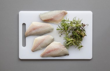 Fish with herbs on the chopping board clipart