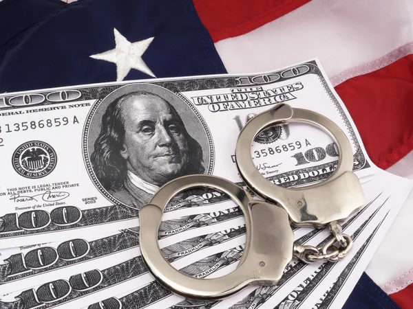 100-Dollar-Scheine und Handschellen über amerikanischer Flagge — Stockfoto
