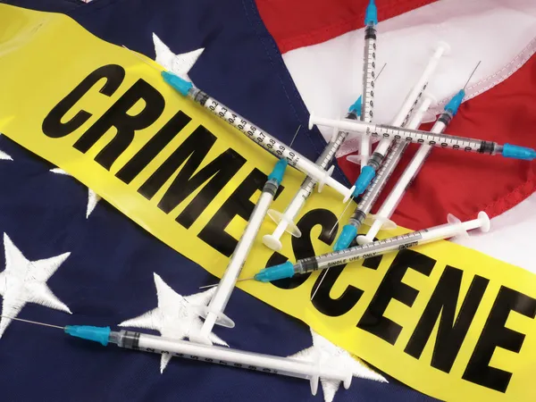 Jeringas y escena del crimen Cinta de cordón sobre bandera estadounidense — Foto de Stock