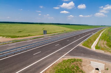 açık yol yol kenarında ve kabarık beyaz bulutlar tarafından yeşil alanlar ile mavi gökyüzü