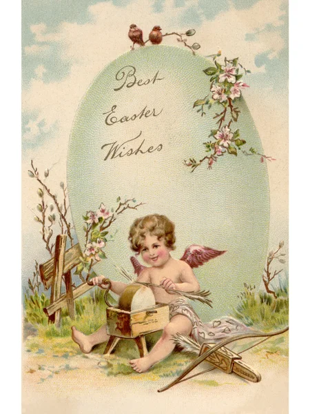 A vintage Easter postcard of a cupid making arrows and a large Easter egg — Stock Photo, Image