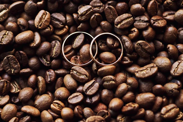 Trauringe auf den Kaffeebohnen lizenzfreie Stockfotos