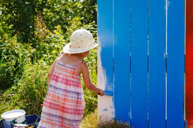 Adorable small girl painting on a fence clipart