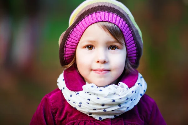 Vacker leende liten flicka i basker utomhus i parken — Stockfoto