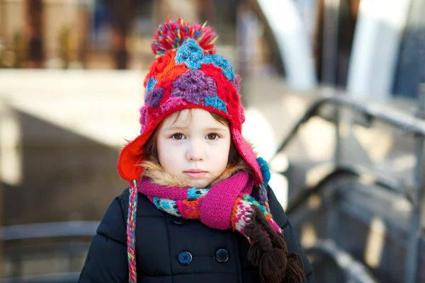 Small adorable girl in hat and knitted scarf looking very dissatisfied — Stock Photo, Image
