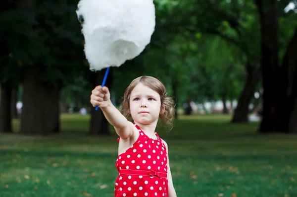 Красивая маленькая девочка ест сахарную вату в парке — стоковое фото