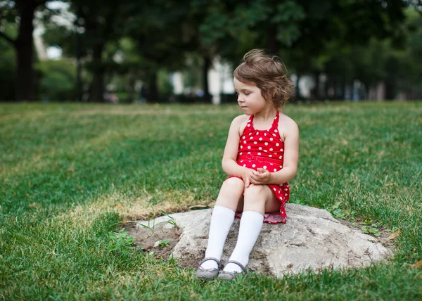 Taş bir parkta otururken çok güzel bebek kız — Stok fotoğraf