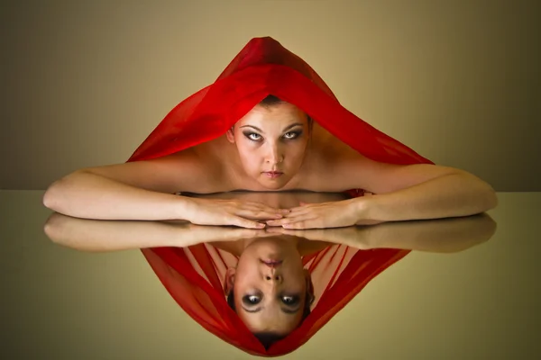 Ein Mädchen mit einer roten Decke im Spiegel — Stockfoto