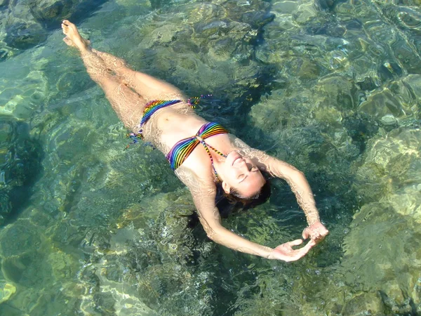 Jeune femme en bikini flottant en eau claire et peu profonde — Photo