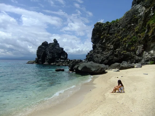 Jovem mulher sentada em uma praia tropical de vestido — Fotografia de Stock